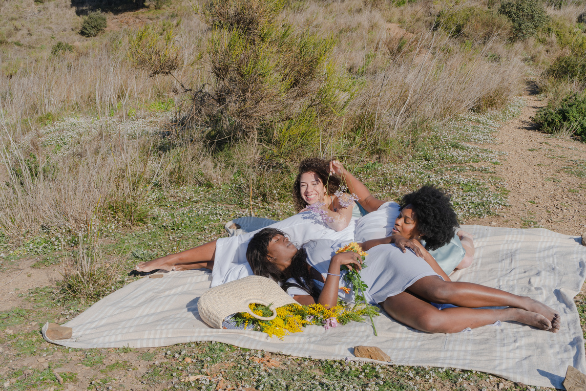Women with Flowers Lying on Picnic Blanket in the Field